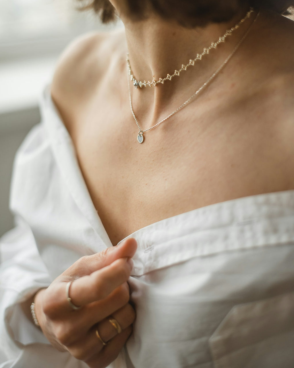 Paperclip chain layered on the neck with an open white shirt