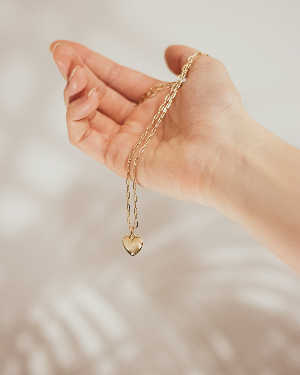 Heart charm necklace held in the hand