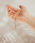 Heart charm necklace held in the hand