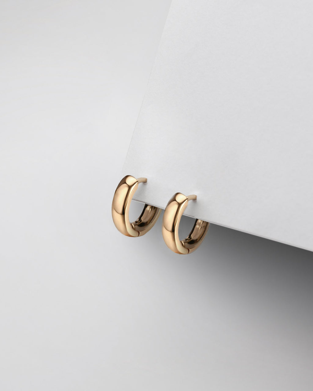 Pair of gold earrings on a white surface