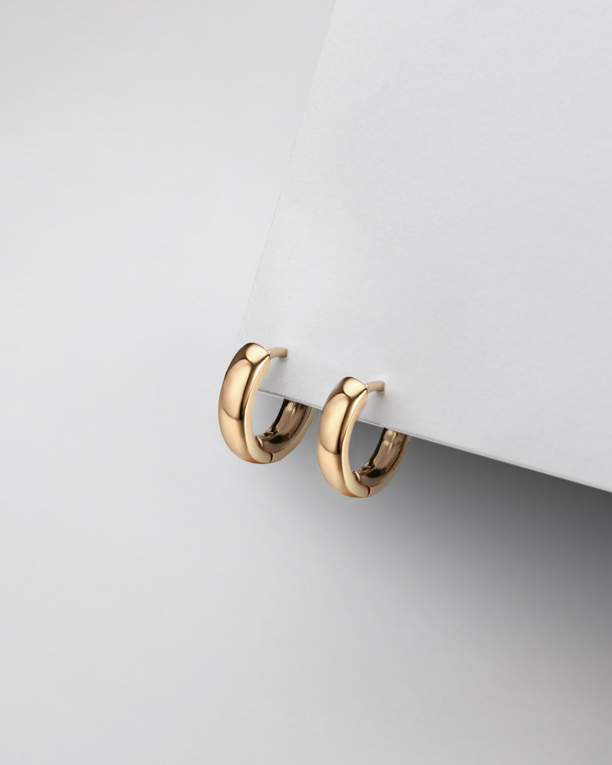 Pair of gold earrings on a white surface