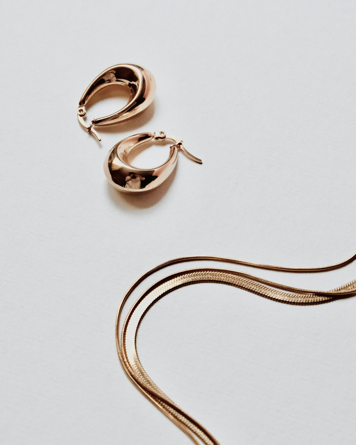 Gold hoop earrings and chain on white
