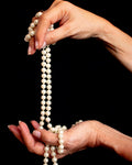 Hands holding a strand of pearls
