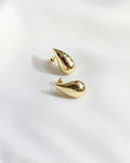 Pair of gold drop earrings on white fabric