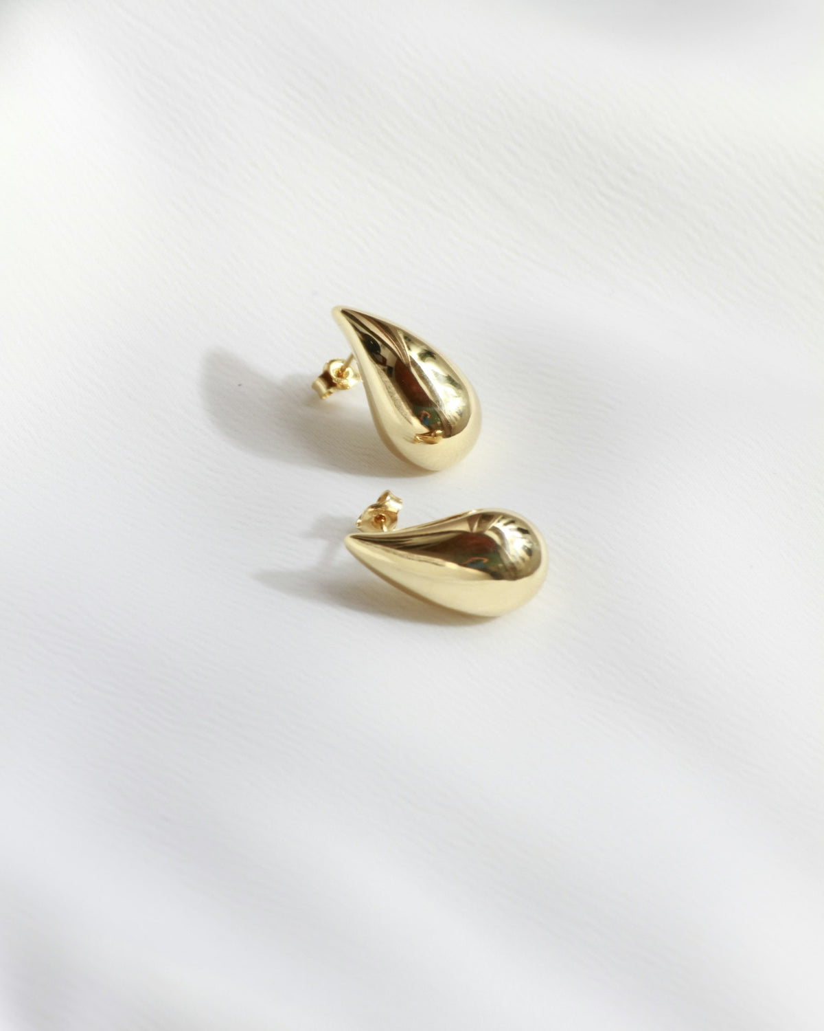 Pair of gold drop earrings on white fabric
