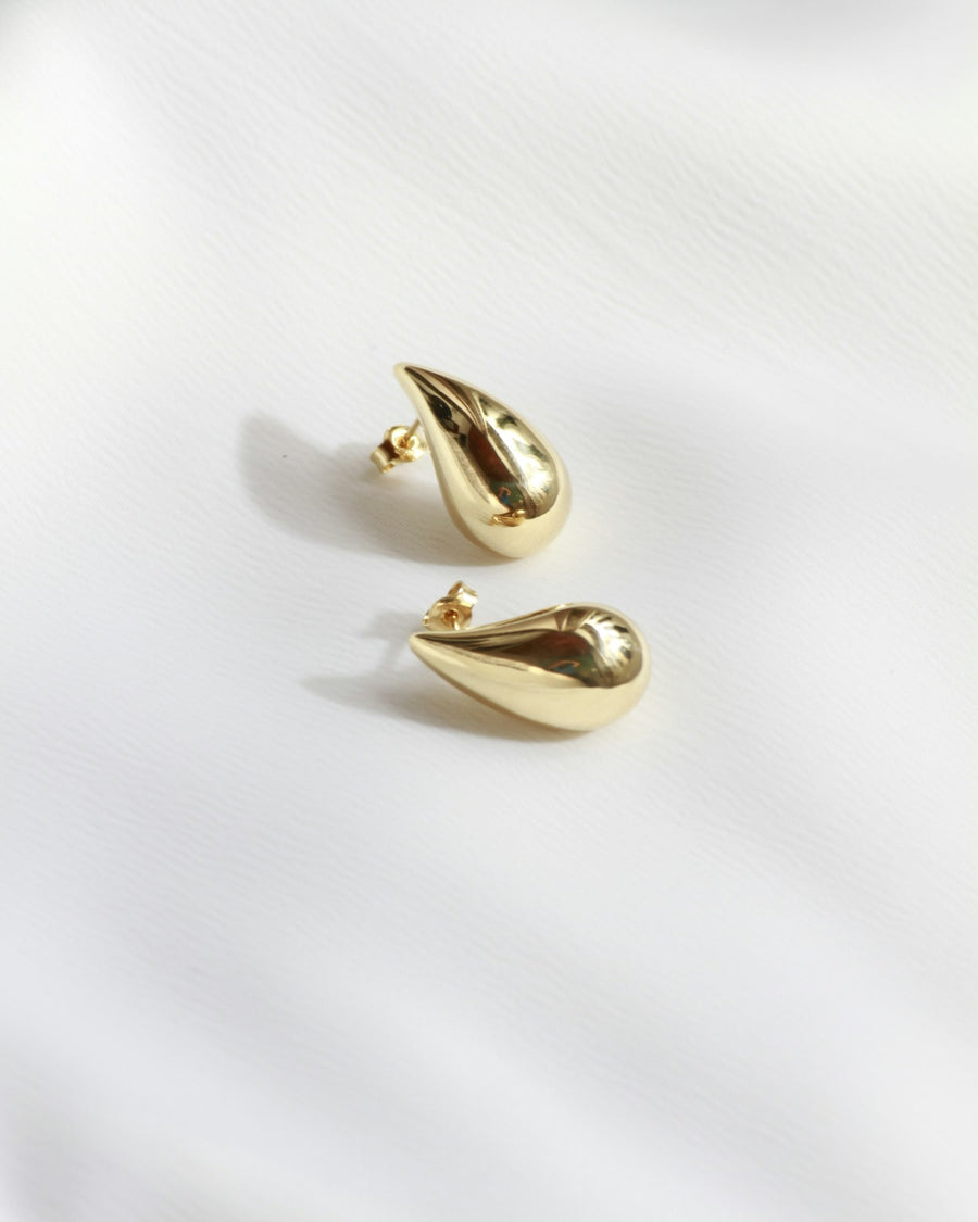 Pair of gold drop earrings on white fabric
