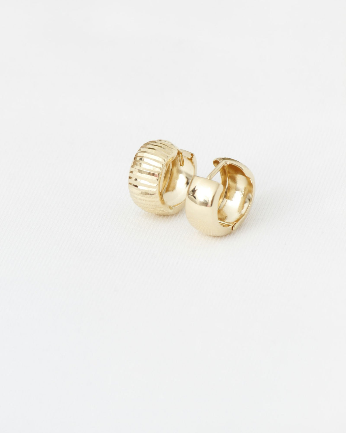 Textured and smooth gold hoop earrings on white