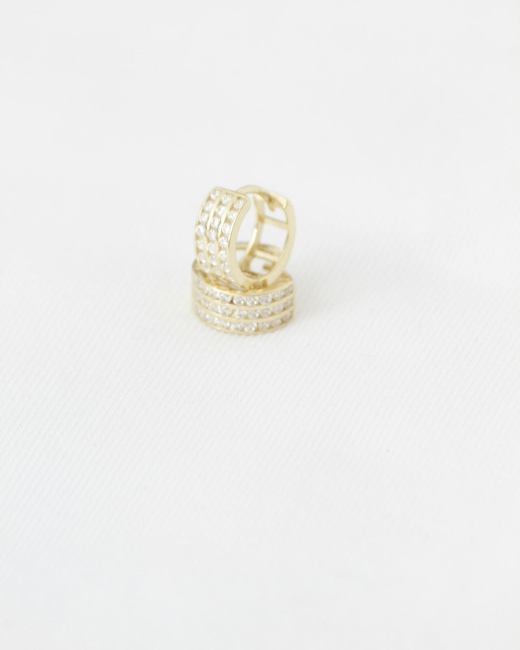 Gold hoop earrings with sparkling stones on white