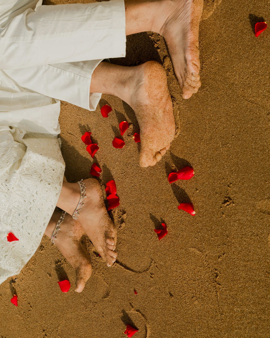 Bare feet on sand with petals
