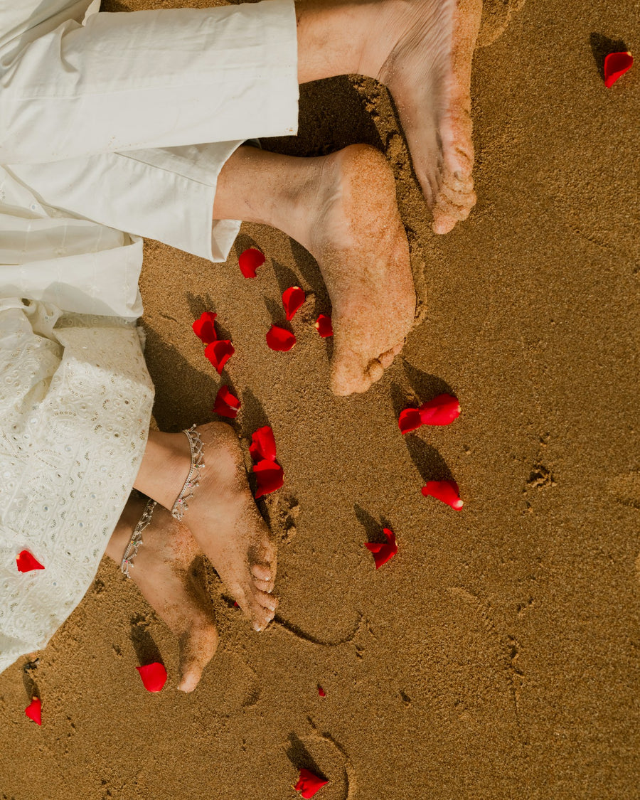 Bare feet on sand with petals