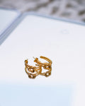 Gold chain-link hoop earrings on a reflective surface